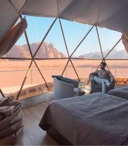 a man sitting in a chair in a tent looking out at the desert at Ahmad Camp Rum in Wadi Rum +71 photos