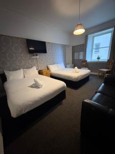 a hotel room with two beds and a couch at Piccolo Guest House in Glasgow +18 photos
