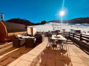 eine Terrasse mit Tischen und Stühlen und ein schneebedeckter Hang in der Unterkunft Bambytwo in Ancelle + 16 Fotos