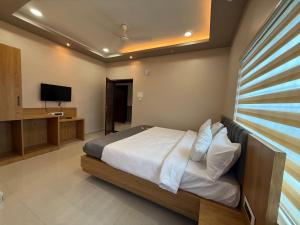 ein Schlafzimmer mit Bett und Flachbildfernseher in der Unterkunft Hotel The Devaraj in Bhubaneshwar