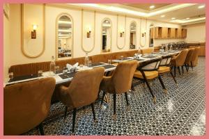 Un comedor con mesas largas y sillas y espejos. en Sea Shell Residency, en Puri