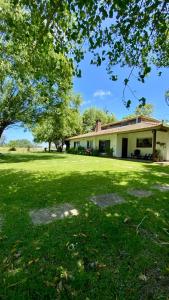 una casa en un patio con un campo verde en Casa Quinta El Refugio, en Villa Gesell