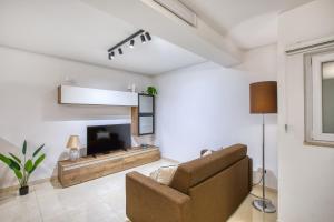 a living room with a couch and a television at Cozy 1 Bedroom Maisonette near Ta Xbiex Marina in Taʼ Xbiex