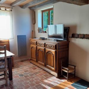 Una sala de estar con un televisor sobre un mueble de madera. en Gîte la petite maison, en Pontchardon