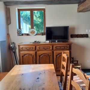 Un comedor con una mesa y un televisor sobre un mueble de madera. en Gîte la petite maison, en Pontchardon