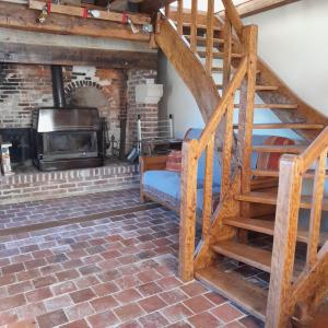Una sala de estar con escalera y chimenea. en Gîte la petite maison, en Pontchardon
