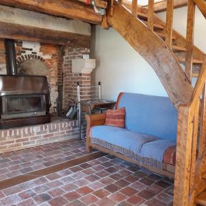 un sofá en una sala de estar con chimenea en Gîte la petite maison, en Pontchardon
