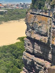 アホイオ・ド・シウヴァにあるApto com Varandas 103 - Balneário Arroio do Silva - 3 minutos do Marのビーチの隣にある岩だらけの崖の空中写真 +22枚の写真