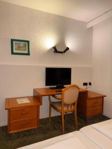 a hotel room with a desk with a television and a bed at Yeti City Hotel Saarbrücken in Saarbrücken