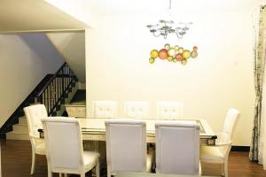 a dining room with a table and white chairs at Mirembe Villas Kigo in Kigo