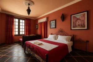 a bedroom with a large bed with red walls at arganier solitaire in Souira Guedima
