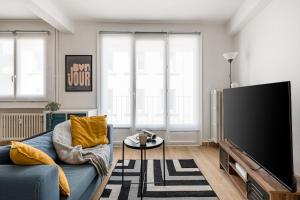 サン・テティエンヌにあるCozy appartement au centre de Saint-Etienneの青いソファと薄型テレビのあるリビングルーム