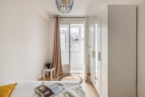 サン・テティエンヌにあるCozy appartement au centre de Saint-Etienneのベッドルーム1室(ベッド1台付)、バルコニーへのドアが備わります。