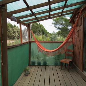 a hammock on a wooden porch with a chair at Chalets rustiques en pleine nature, L'ARCHIPEL in Punta Del Diablo