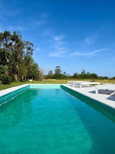 Una piscina con agua azul en un patio. en Casa Quinta El Refugio, en Villa Gesell