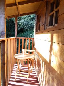 Una mesa y una silla de madera en el porche de una cabaña. en La cabaña, en Tlazala de Fabela