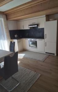 a kitchen with white cabinets and a table with chairs at Lackenhof in Rauris