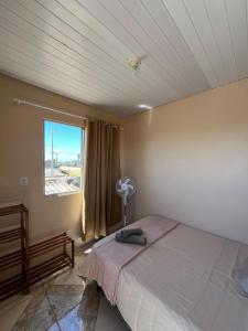 Schlafzimmer mit einem Bett und einem Fenster mit einem Ventilator in der Unterkunft Casa Praia do Hermenegildo in Santa Vitória do Palmar