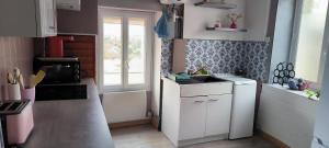 een kleine keuken met witte kasten en een raam bij La ville haute in Chauvigny