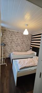 Dos camas en una habitación con una pared de ladrillo. en rakentajanpolku 1, en Rovaniemi