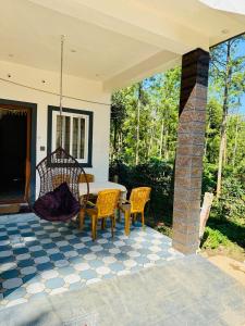 a patio with a table and chairs on a house at Sanju's Homestay in Attigundi