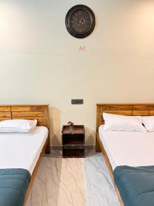 two beds in a room with a clock on the wall at Sanju's Homestay in Attigundi +2 photos
