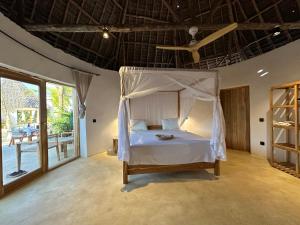 een slaapkamer met een hemelbed en een balkon bij GARDEN EDEN Lodge in Jambiani +31 foto's
