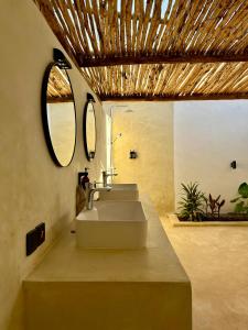 een badkamer met 3 wastafels en een spiegel bij GARDEN EDEN Lodge in Jambiani