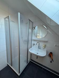 une salle de bain blanche avec une douche et un lavabo dans l'établissement Ferienwohnungen Avenor, à Norden 7 autres photos