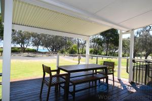 a picnic table and chairs on a deck with a view of a park at 1 The Esplanade in Woodgate