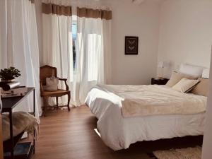 a white bedroom with a bed and a window at La demeure des vignes in Murato