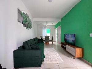 ein grünes Wohnzimmer mit einer Couch und einem Fernseher in der Unterkunft Residencial Passos 2 in Guaratuba