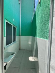 ein grün-weißes Badezimmer mit Waschbecken und Spiegel in der Unterkunft Residencial Passos 2 in Guaratuba + 41 Fotos