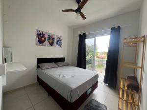 Schlafzimmer mit einem Bett, einem Deckenventilator und einem Fenster in der Unterkunft Residencial Passos 2 in Guaratuba