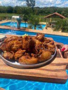 um prato de comida em uma mesa ao lado de uma piscina em Pousada São Sebastião em São Sebastião do Rio Verde