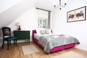 a bedroom with a bed and a chair and a window at Zacisze Teremiski in Białowieża