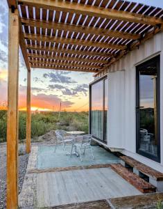 a patio with a table and chairs under a pergola at Cabaña Container en Viñedos in San Rafael