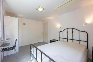 a white bedroom with a bed and a chair at Jonkerstee 21 - Ouddorp in Ouddorp