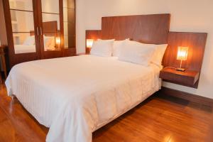 Un dormitorio con una gran cama blanca y dos lámparas. en Parc Royal Suites Hotel, en Cuenca