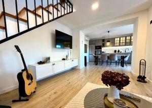 a living room with a guitar and a kitchen at Villa Billubium - Dalmatian Stone House with Private Heated Pool in Zovko