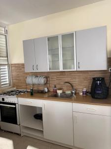 a kitchen with white cabinets and a sink at דירת ציון in Petaẖ Tiqwa