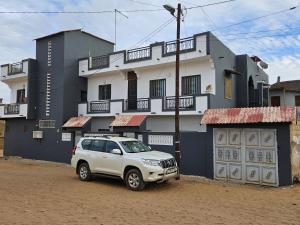 a white suv parked in front of a building at Residence Ganou Mboro in Mboro