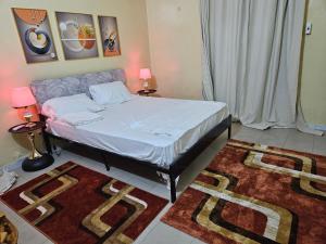 a bed in a room with two tables and two lamps at Residence Ganou Mboro in Mboro
