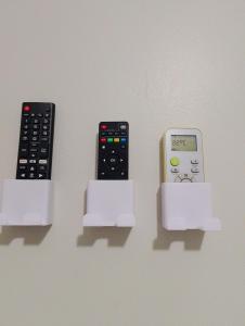 due telecomandi e un cellulare in un supporto di Pousada Solluar a Paracatu