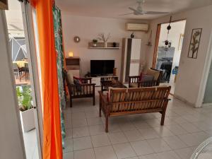 a living room with a couch and chairs and a television at Villa Atlantis 3 chambres in Port-Louis
