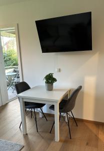 a white table with chairs and a tv on a wall at Ferienwohnung Lüttje Mööv 2 an der Nordsee in Wangerland