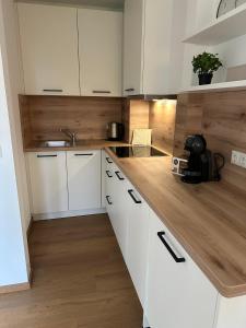 a kitchen with white cabinets and a wooden counter top at Ferienwohnung Lüttje Mööv 2 an der Nordsee in Wangerland