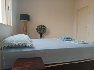 una camera da letto con un grande letto bianco e un ventilatore di Capsula Residence Hotel a Marília