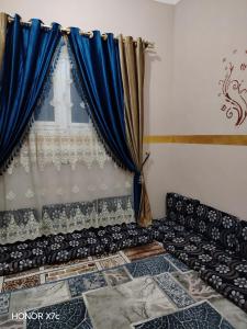 um sofá em frente a uma janela com cortinas azuis em البيت السيوي em Oásis de Siuá