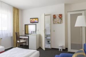 une chambre d'hôtel avec un lit, un bureau et une table dans l'établissement Aparthotel VEGA, à Berlin